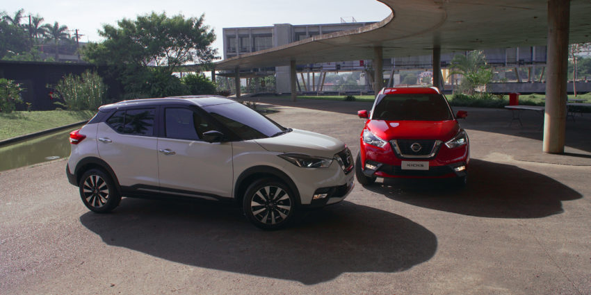 Nissan Kicks 2020 branco e vermelho lado a lado em pátio de um edíficio