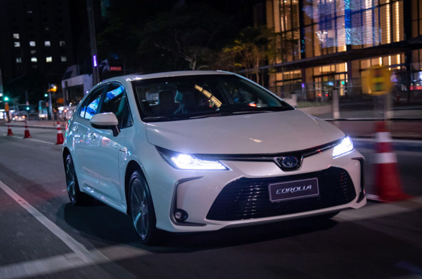 Toyota Corolla 2020 branco visto desde frente na rua a noite com faróis acesos